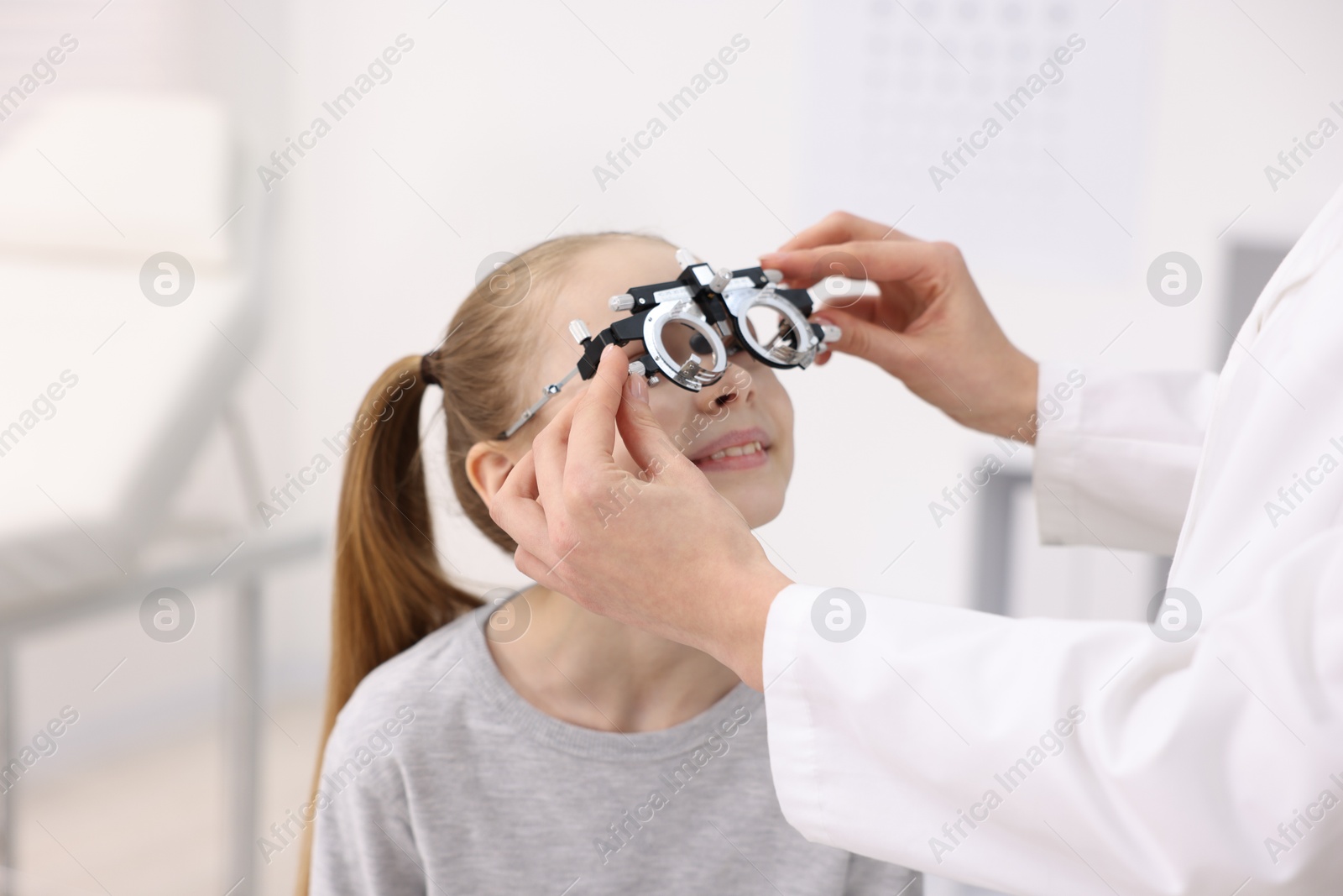 Photo of Ophthalmologist examining girl's vision with trial frame in clinic, closeup