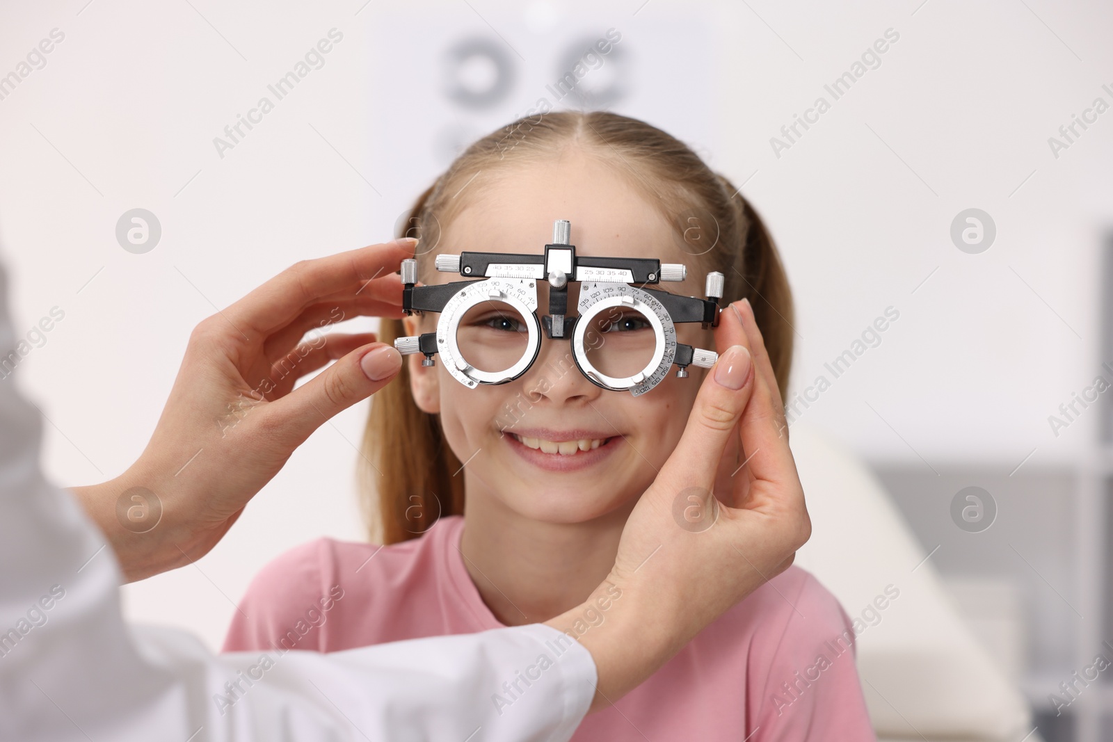 Photo of Ophthalmologist examining girl's vision with trial frame in clinic, closeup