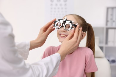 Photo of Ophthalmologist examining girl's vision with trial frame in clinic, closeup