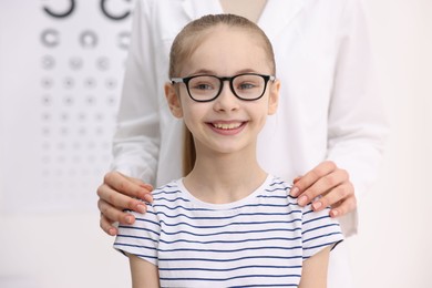 Photo of Little girl with glasses and ophthalmologist in office