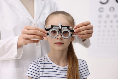 Photo of Ophthalmologist examining girl's vision with trial frame in clinic, closeup