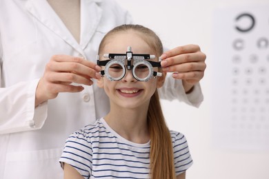 Photo of Ophthalmologist examining girl's vision with trial frame in clinic, closeup