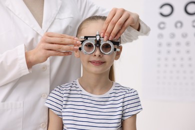 Photo of Ophthalmologist examining girl's vision with trial frame in clinic, closeup