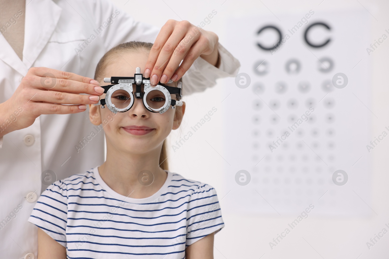 Photo of Ophthalmologist examining girl's vision with trial frame in clinic, closeup. Space for text