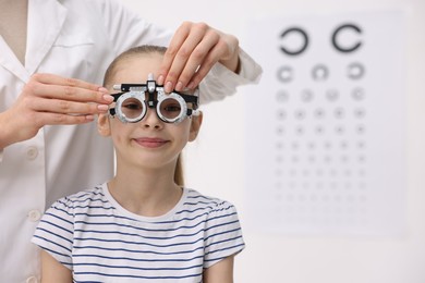 Photo of Ophthalmologist examining girl's vision with trial frame in clinic, closeup. Space for text