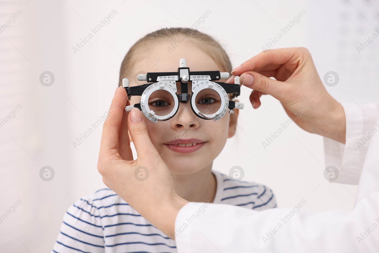 Photo of Ophthalmologist examining girl's vision with trial frame in clinic, closeup