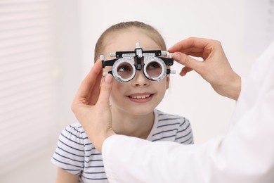 Photo of Ophthalmologist examining girl's vision with trial frame in clinic, closeup