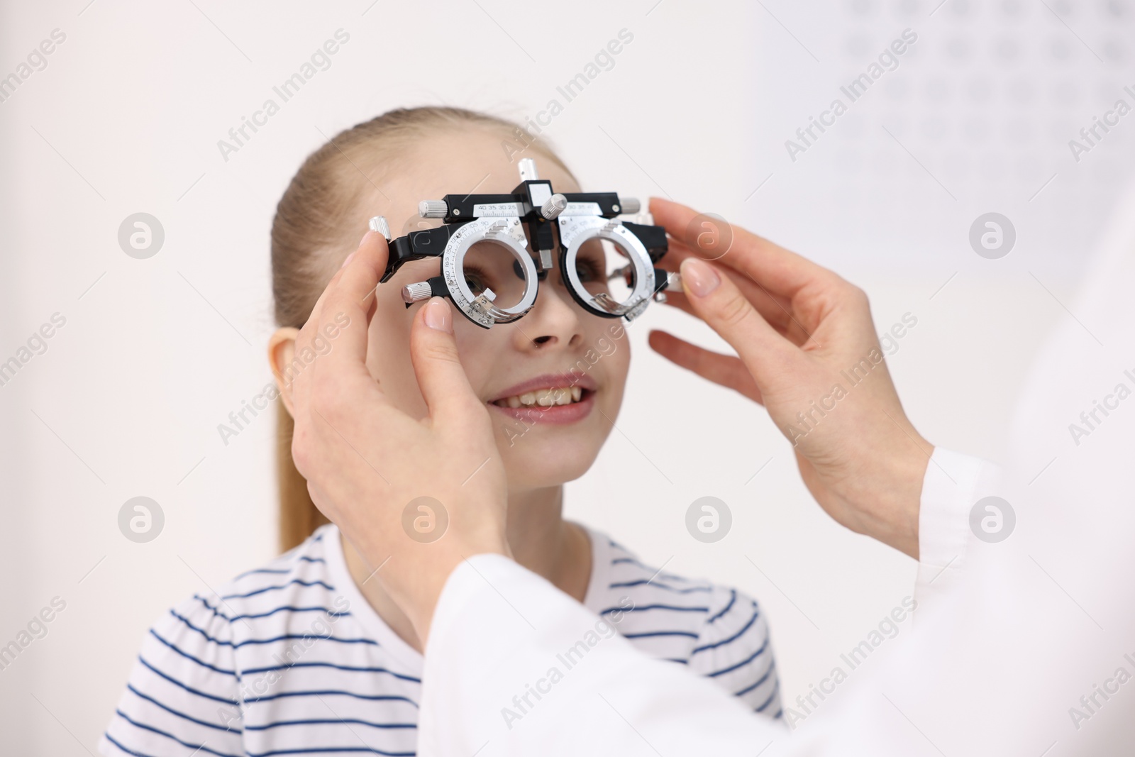 Photo of Ophthalmologist examining girl's vision with trial frame in clinic, closeup