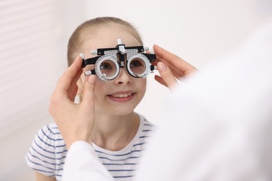 Photo of Ophthalmologist examining girl's vision with trial frame in clinic, closeup