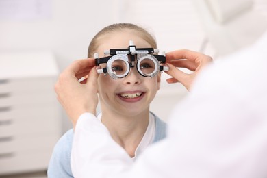 Photo of Ophthalmologist examining girl's vision with trial frame in clinic, closeup