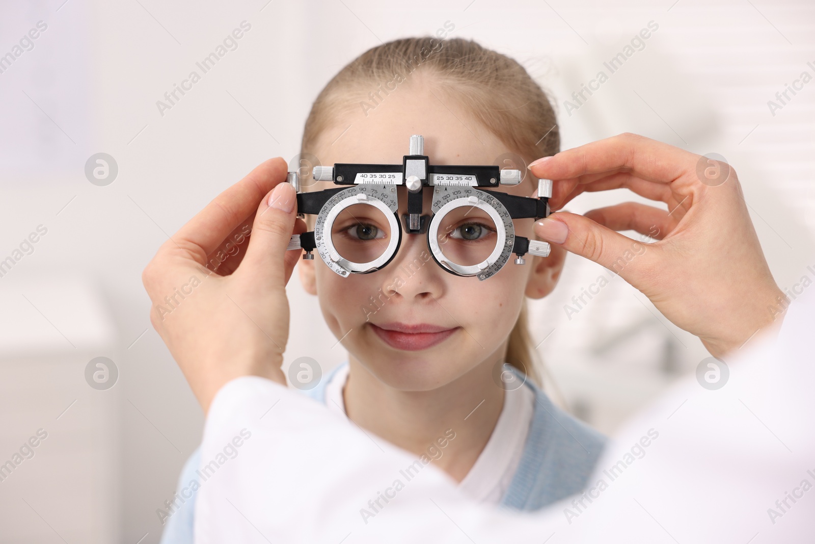 Photo of Ophthalmologist examining girl's vision with trial frame in clinic, closeup