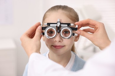 Photo of Ophthalmologist examining girl's vision with trial frame in clinic, closeup