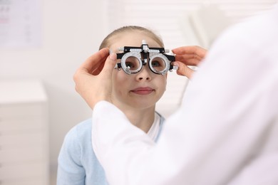 Photo of Ophthalmologist examining girl's vision with trial frame in clinic, closeup