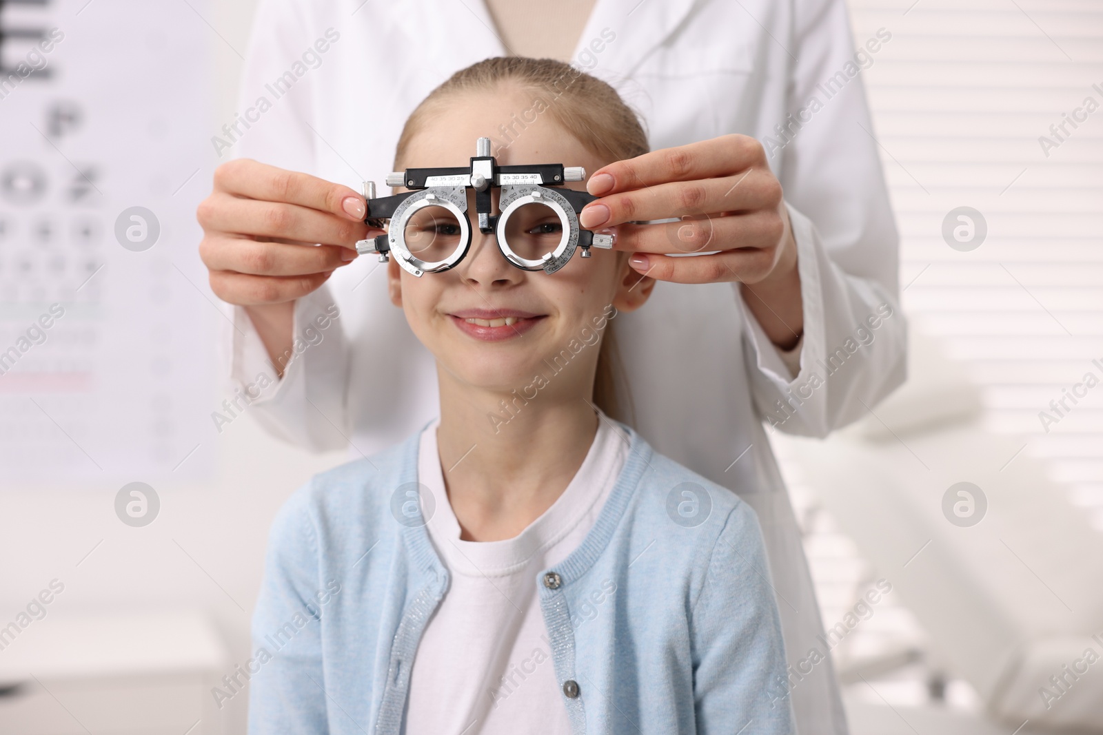 Photo of Ophthalmologist examining girl's vision with trial frame in clinic, closeup