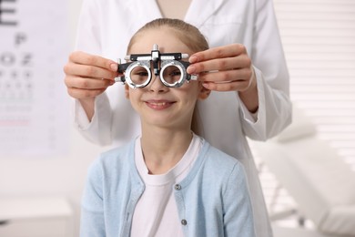 Photo of Ophthalmologist examining girl's vision with trial frame in clinic, closeup