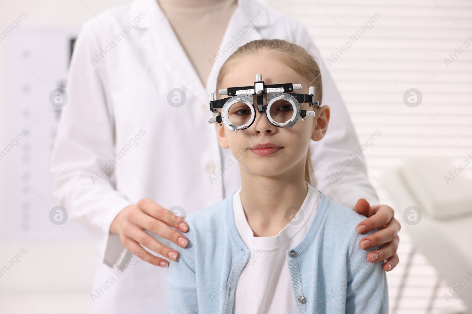 Photo of Ophthalmologist examining girl's vision with trial frame in clinic, closeup