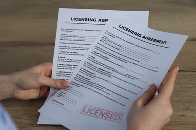 Photo of Woman with licensing agreement documents at wooden table, closeup