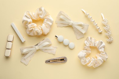 Different hair accessories on beige background, flat lay