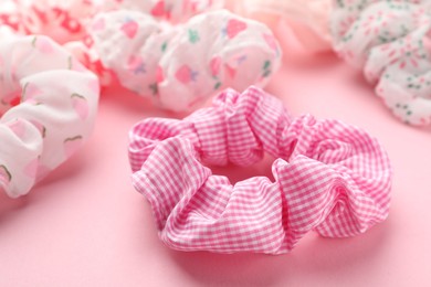 Different hair scrunchies on pink background, closeup