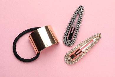 Different hair accessories on pink background, flat lay