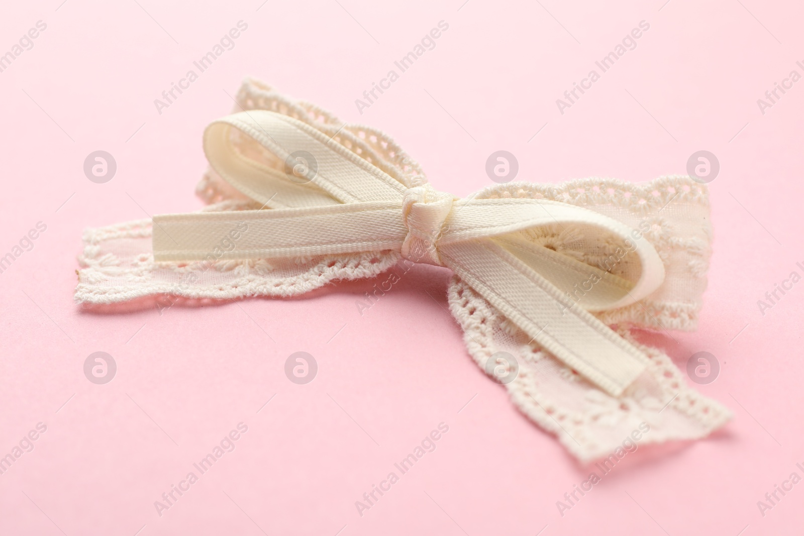 Photo of Beautiful hair bow on pink background, closeup