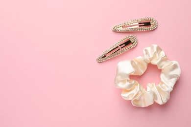 Photo of Hair clips and scrunchie on pink background, flat lay. Space for text