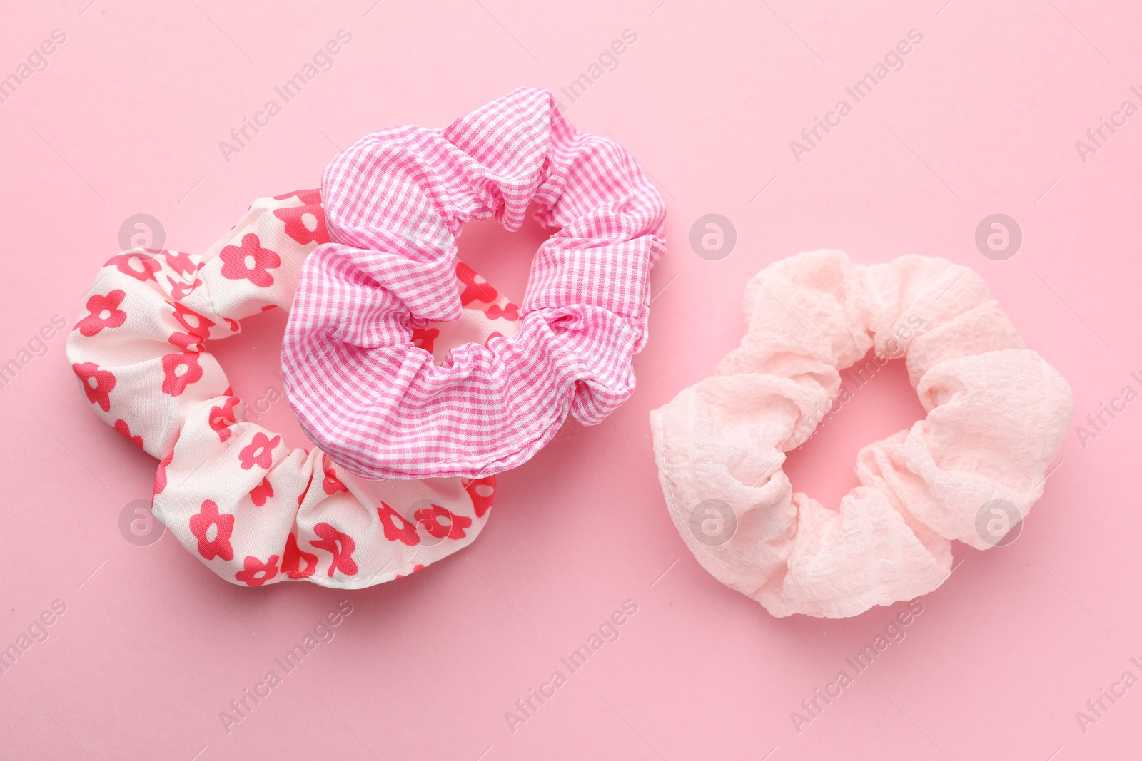 Photo of Different hair scrunchies on pink background, flat lay