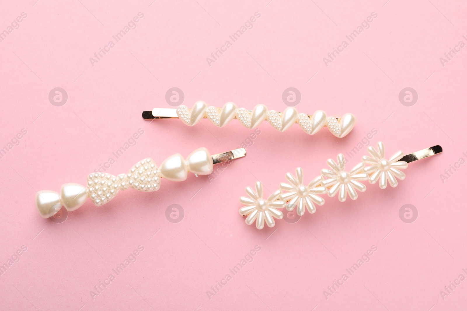 Photo of Different hair clips on pink background, flat lay