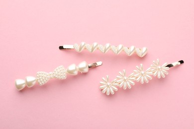 Different hair clips on pink background, flat lay