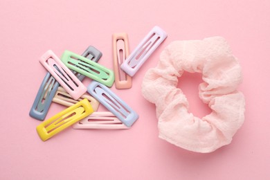 Hair clips and scrunchie on pink background, flat lay