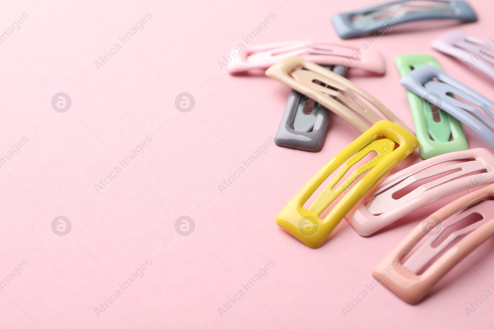 Photo of Different hair clips on pink background, closeup. Space for text