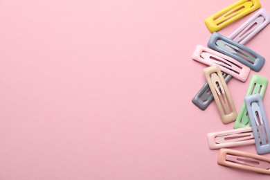 Different hair clips on pink background, flat lay. Space for text