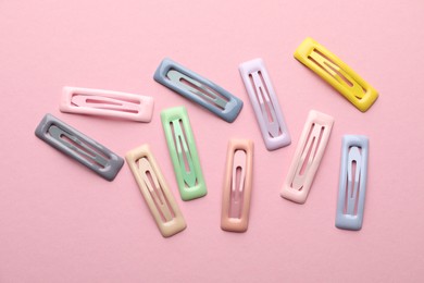 Different hair clips on pink background, flat lay