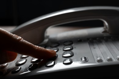 Photo of Woman dialing number on landline telephone, closeup