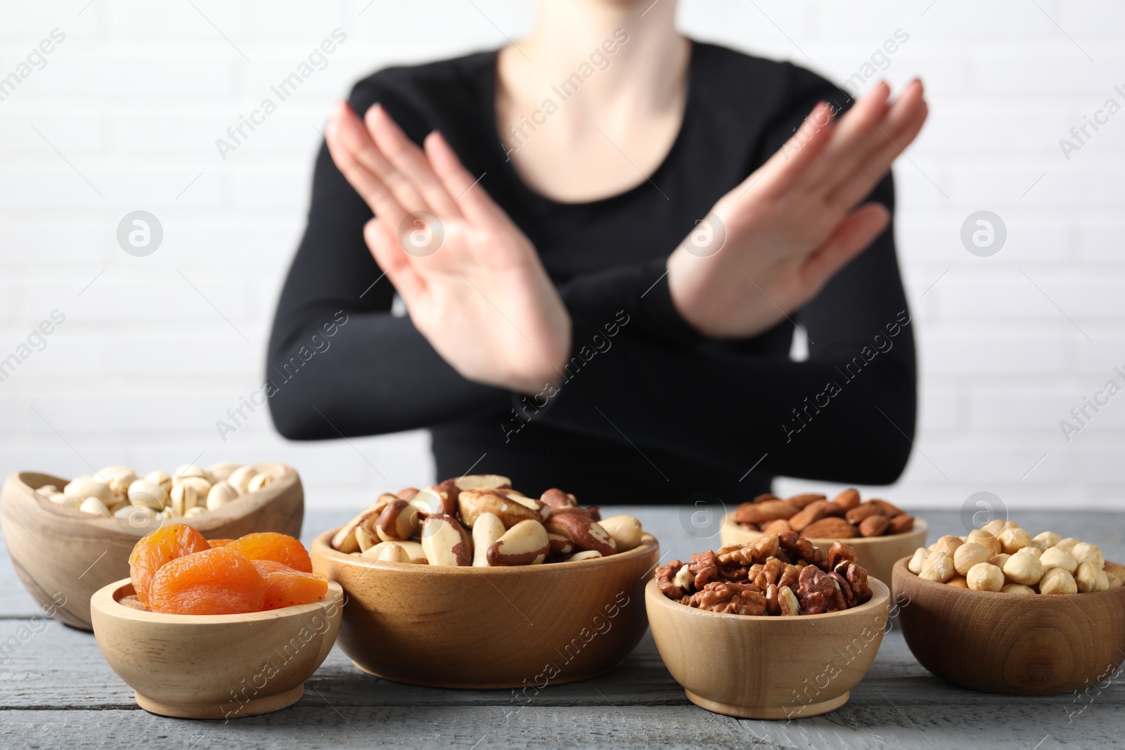 Photo of Woman refusing to eat products at grey wooden table, selective focus. Food allergy concept