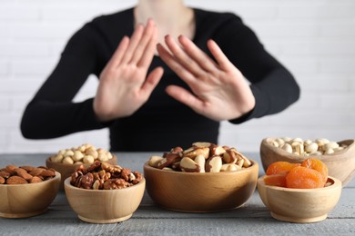 Photo of Woman refusing to eat products at grey wooden table, selective focus. Food allergy concept