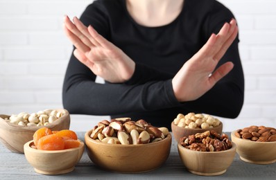 Photo of Woman refusing to eat products at grey wooden table, selective focus. Food allergy concept