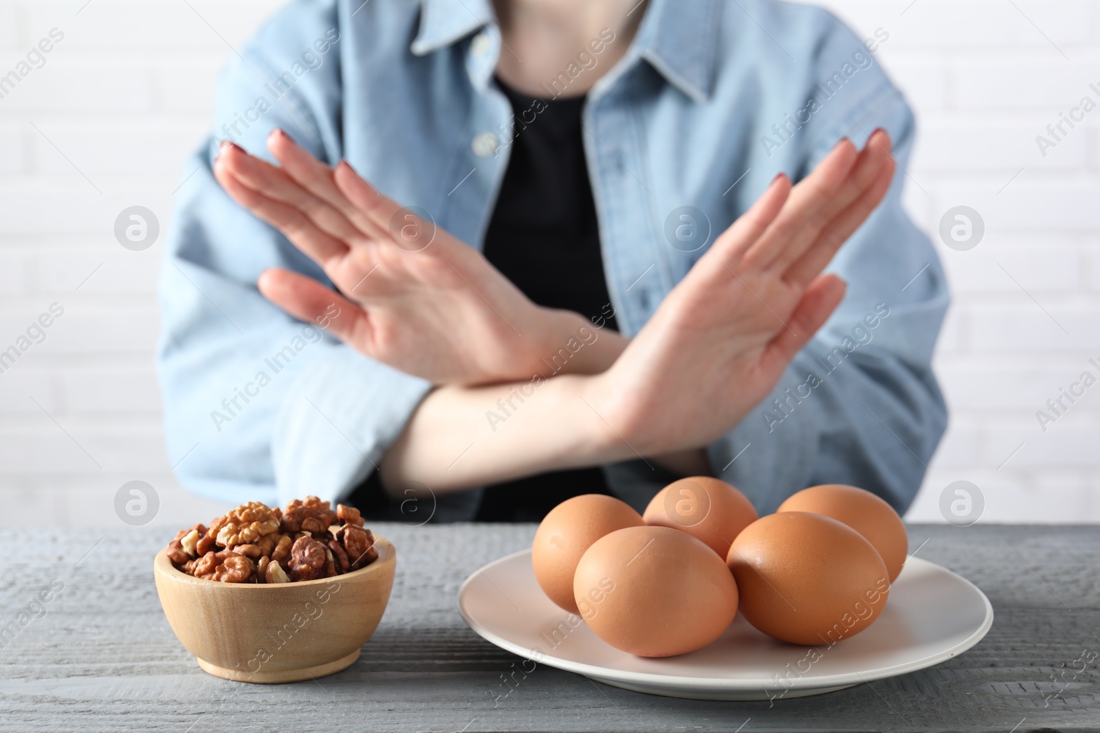 Photo of Woman refusing to eat products at grey wooden table, selective focus. Food allergy concept