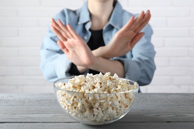 Photo of Woman refusing to eat popcorn at grey wooden table, selective focus. Food allergy concept