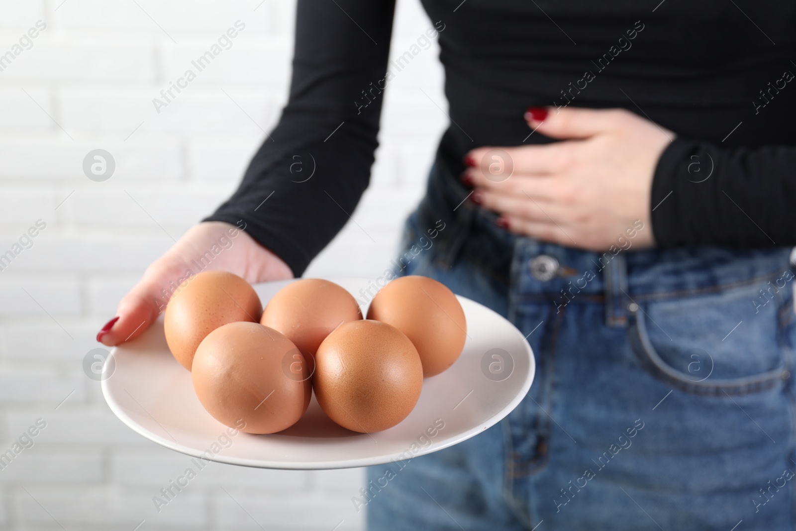 Photo of Woman refusing to eat eggs near white brick wall, closeup. Food allergy concept