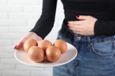 Photo of Woman refusing to eat eggs near white brick wall, closeup. Food allergy concept