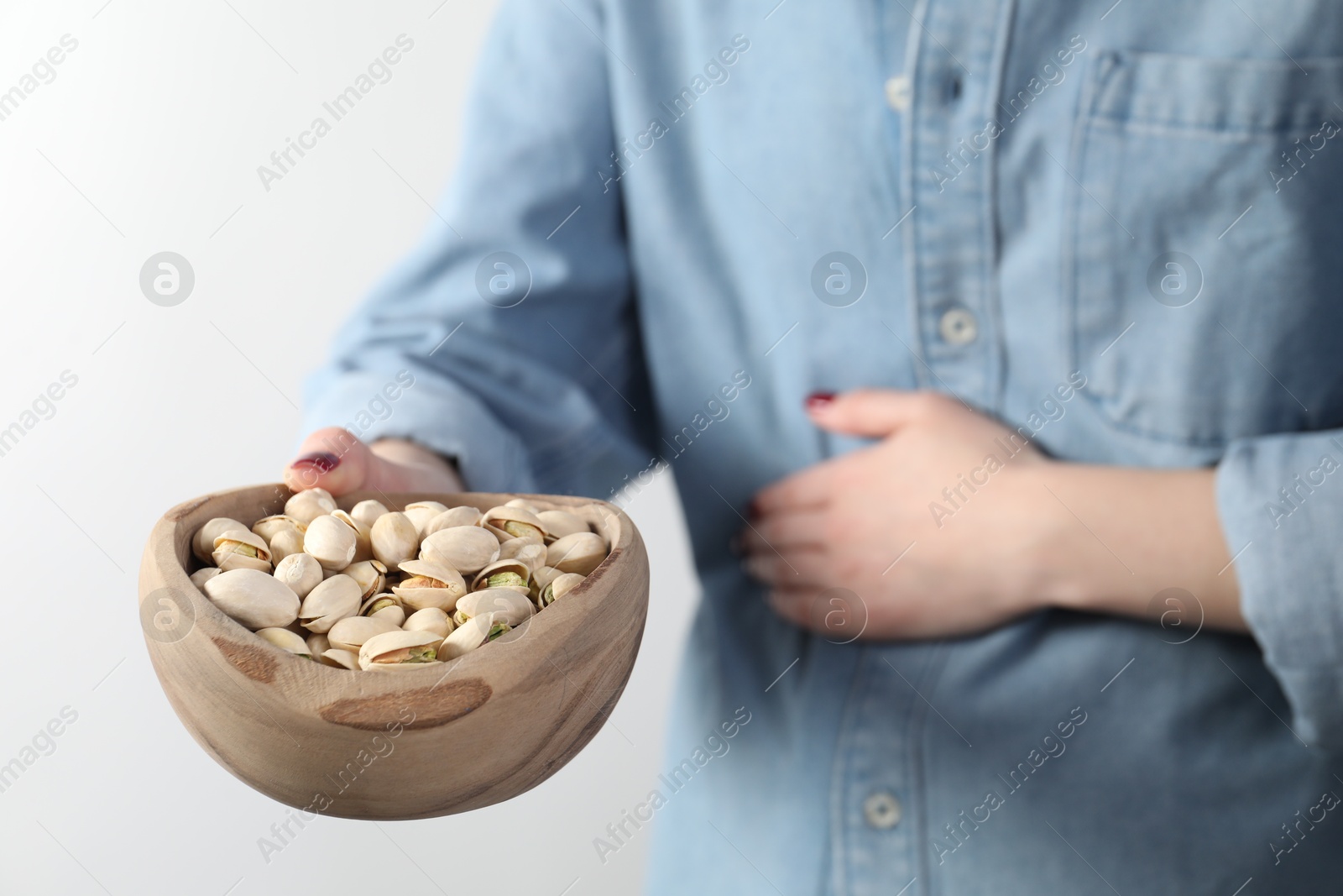 Photo of Woman refusing to eat pistachios on white background, closeup. Food allergy concept