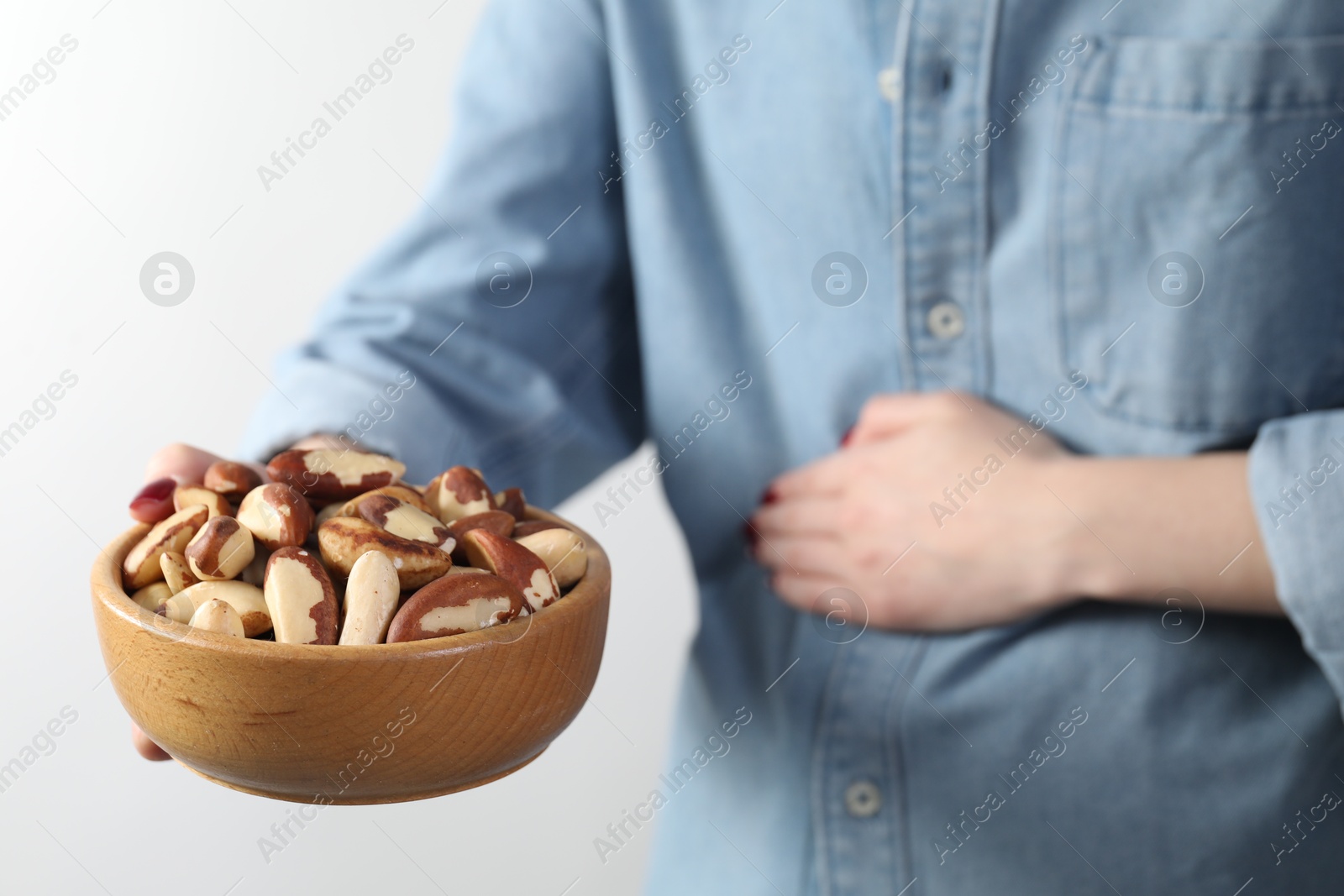 Photo of Woman refusing to eat Brazil nuts on white background, closeup. Food allergy concept