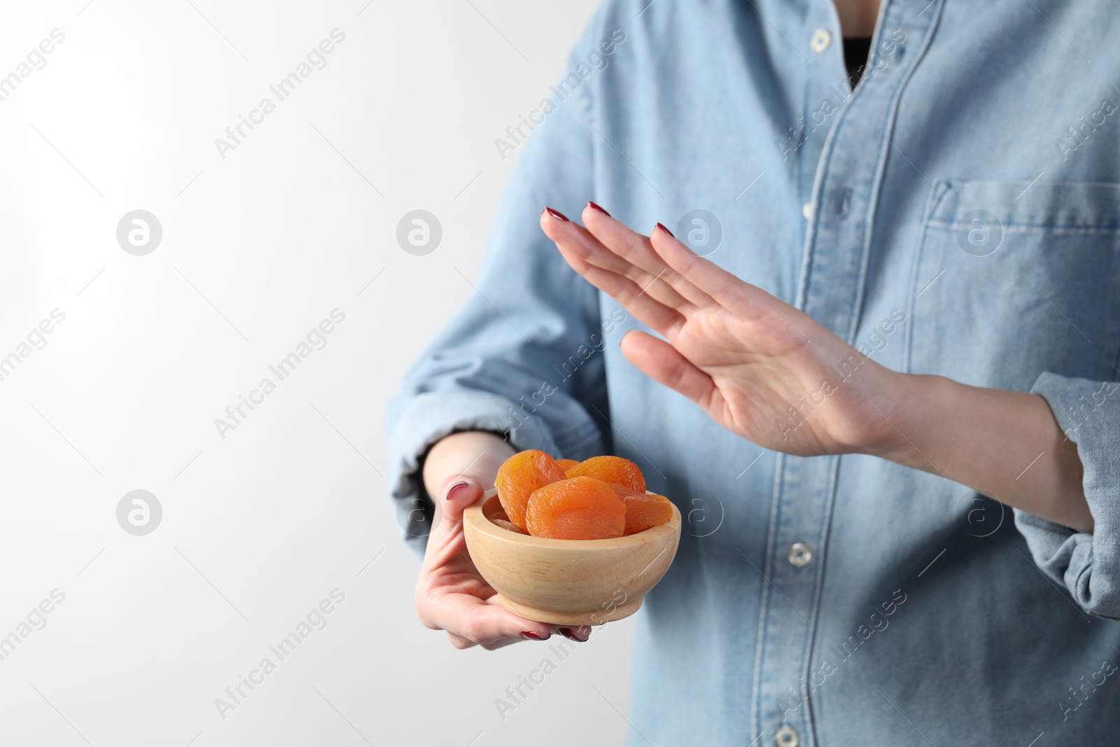 Photo of Food allergy concept. Woman refusing to eat dried apricots on white background, closeup. Space for text