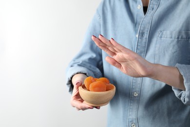 Photo of Food allergy concept. Woman refusing to eat dried apricots on white background, closeup. Space for text