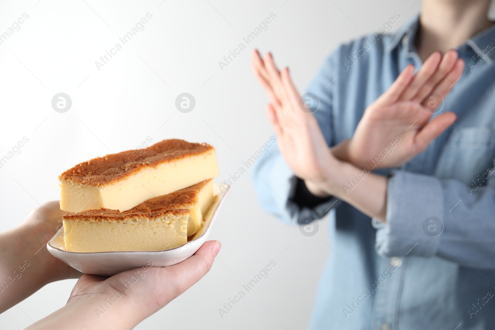 Photo of Woman refusing cheesecake on white background, , selective focus. Food allergy concept