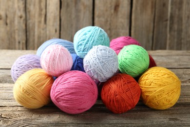 Photo of Balls of colorful yarn on wooden table, closeup