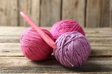 Photo of Balls of colorful yarn and crochet hook on wooden table, closeup