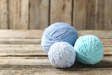 Photo of Balls of colorful yarn on wooden table, closeup. Space for text