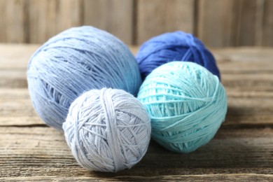 Photo of Balls of colorful yarn on wooden table, closeup